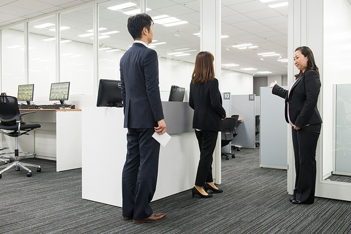 試験会場へ受験生二人が入ろうとしている様子の写真。試験監督員がドアの脇に立っている。
