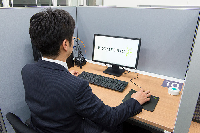 個別のブースで受験用のPCを前に受験生が着席している様子の写真。