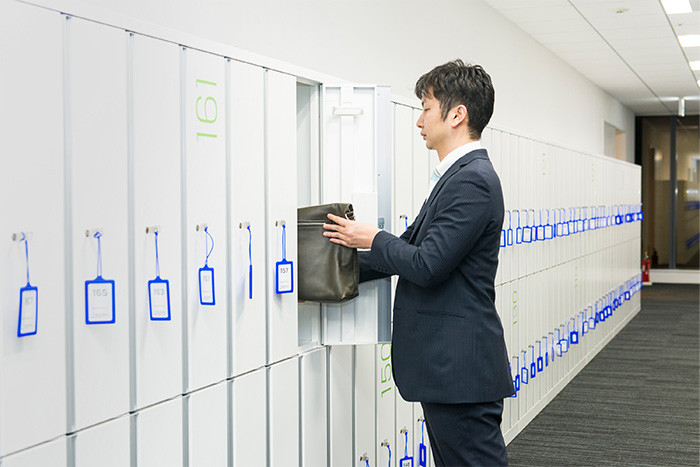 試験会場のロッカーに受験生が荷物をしまっている写真。